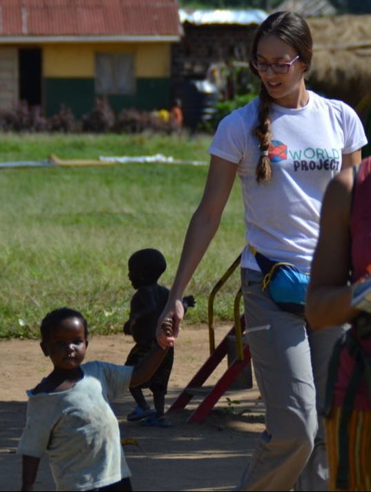 niño en Zinga que camina con voluntaria asociacion worldproject